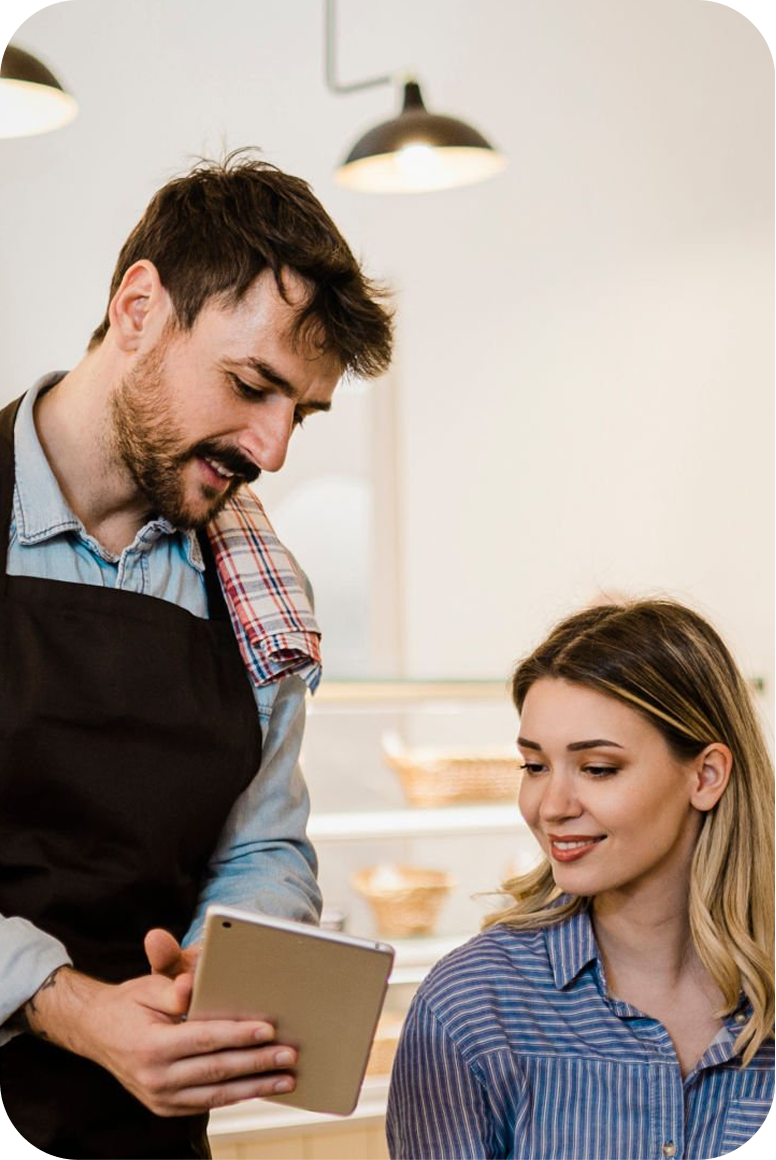 Encargado de una cafetería revisando el negocio en una tablet junto a una clienta